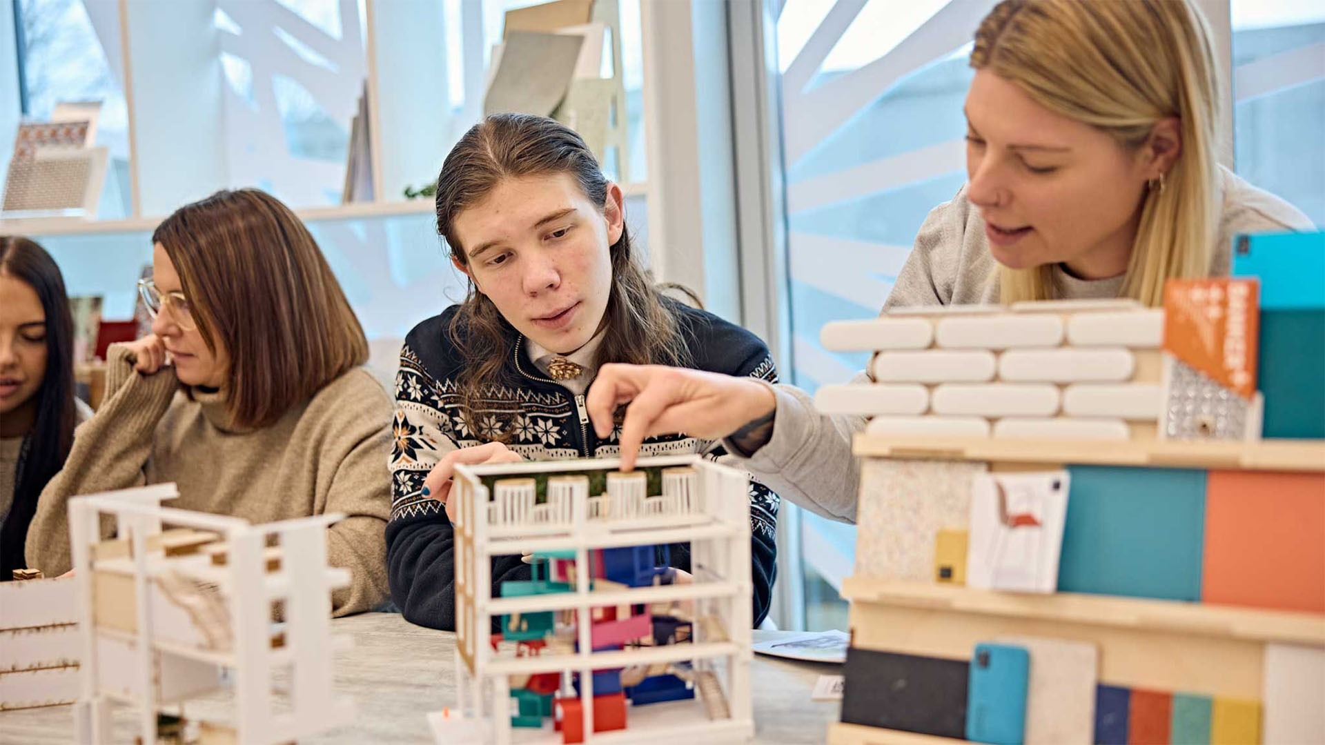 Students looking at various home models in the interior design group work space