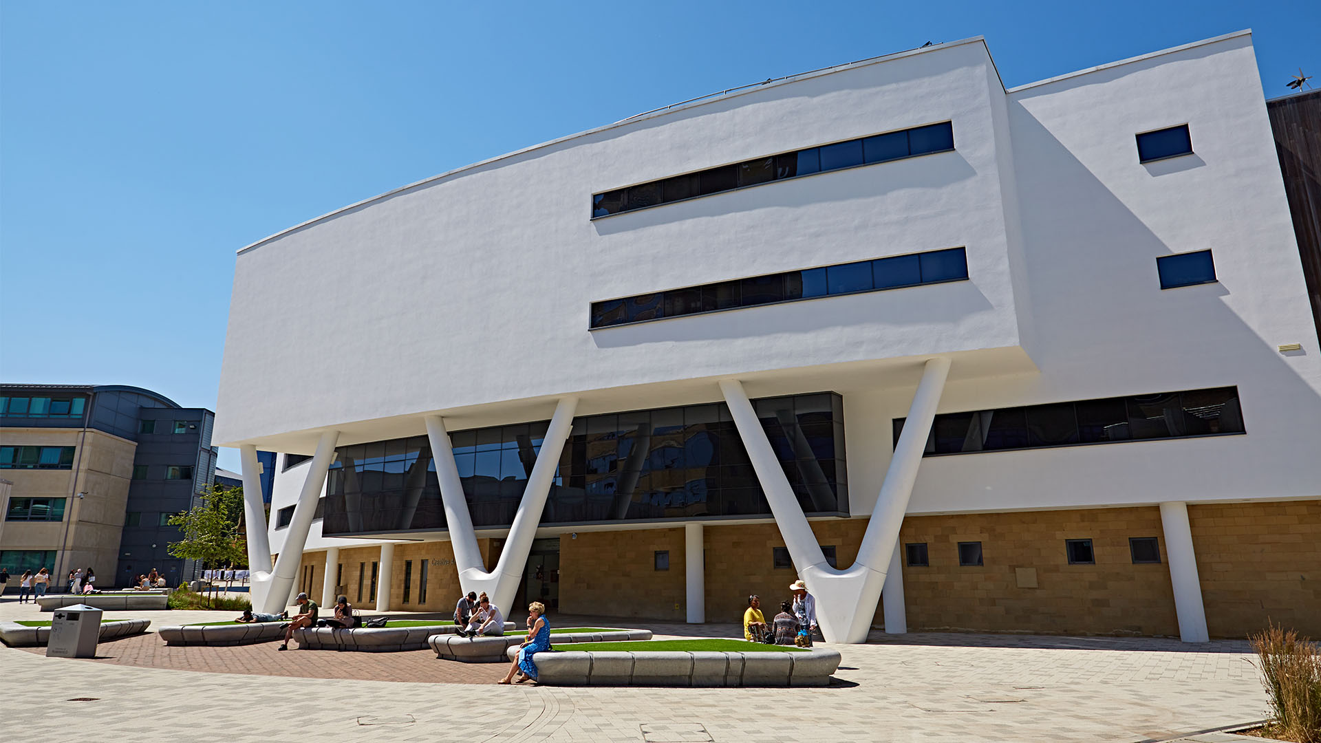 Richard Steinitz building in the sunlight with staff and students sat infront