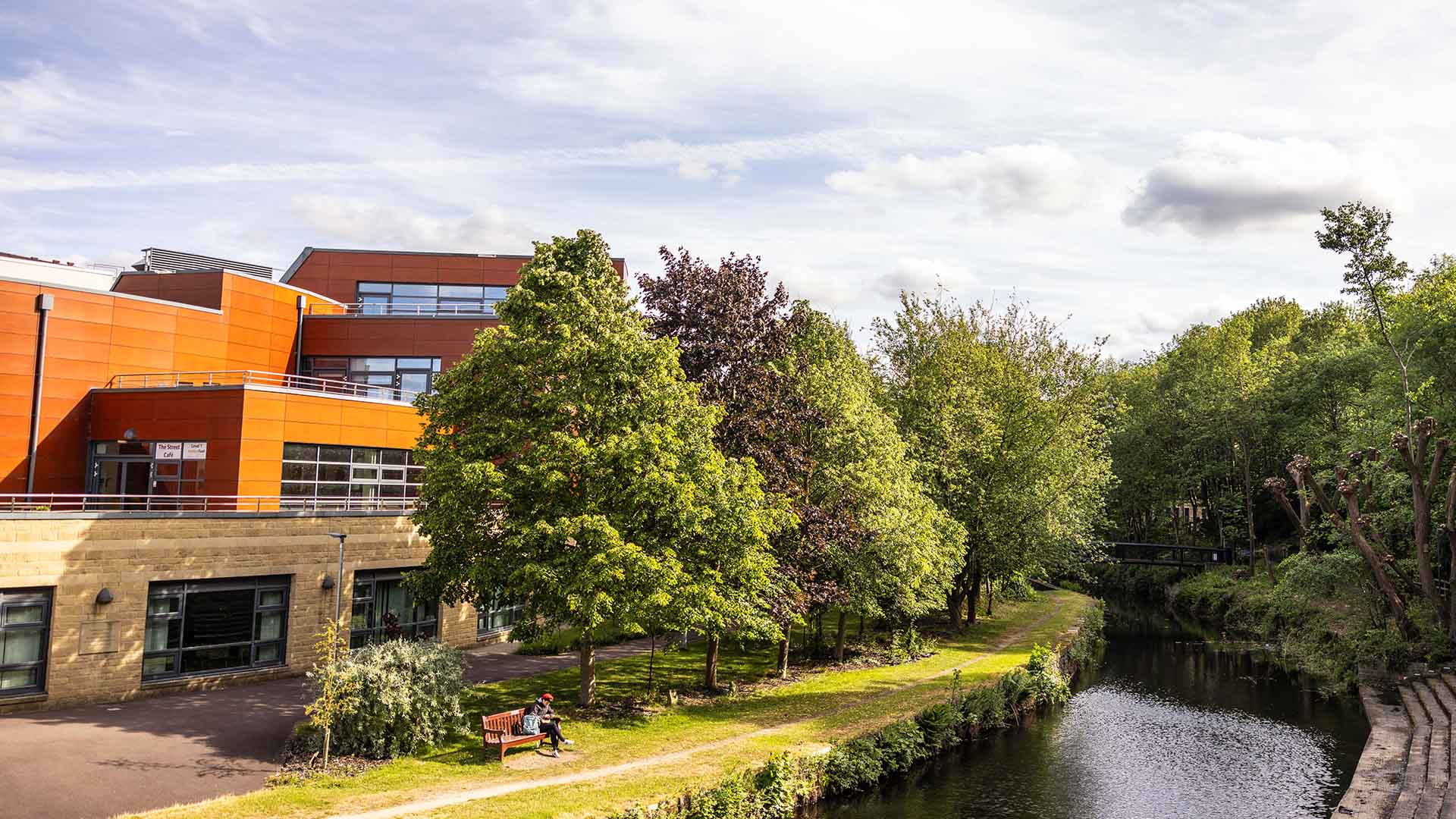 Huddersfield Business School behind canal and trees