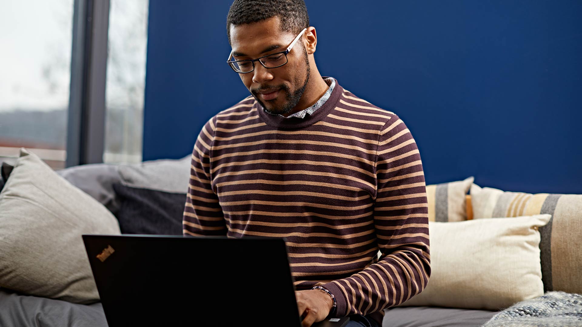 A student sat on their bed, working on a laptop.