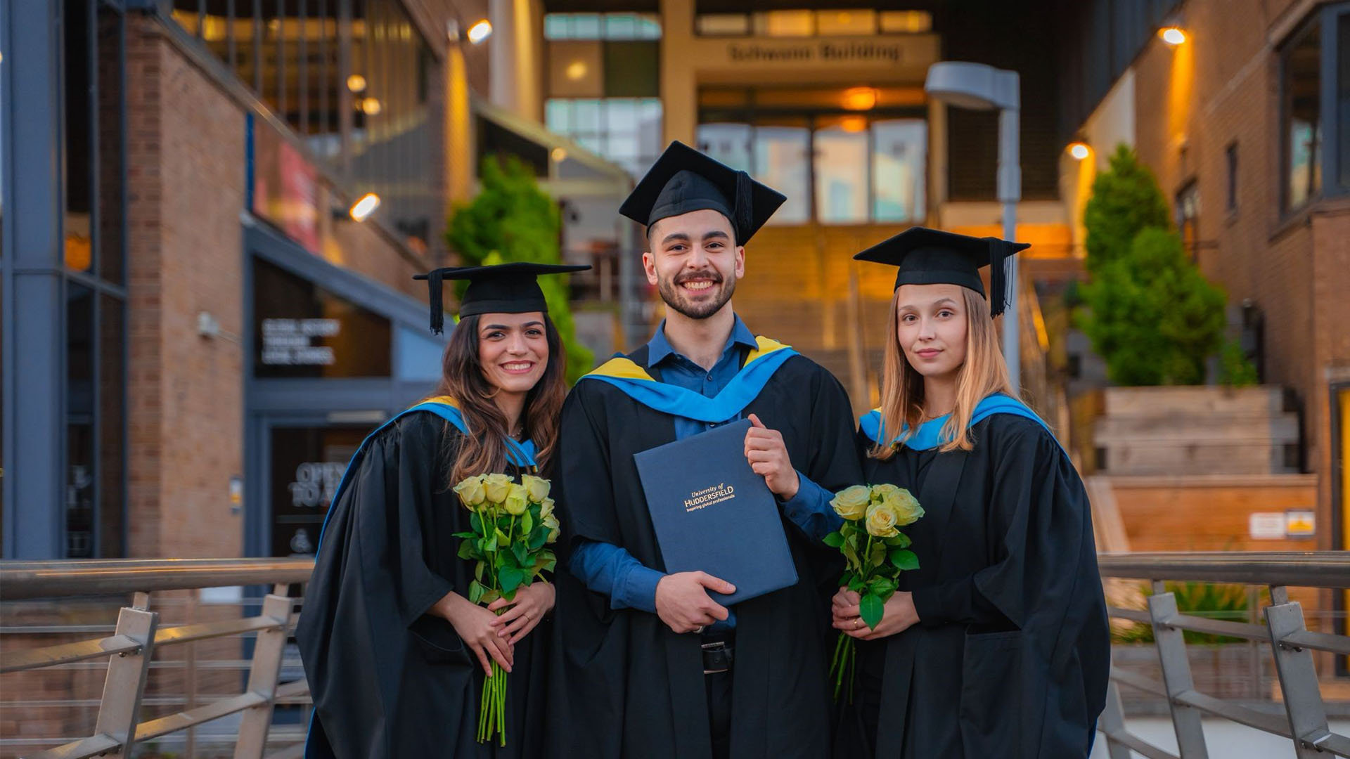 Three graduates posing for a picture with flowers