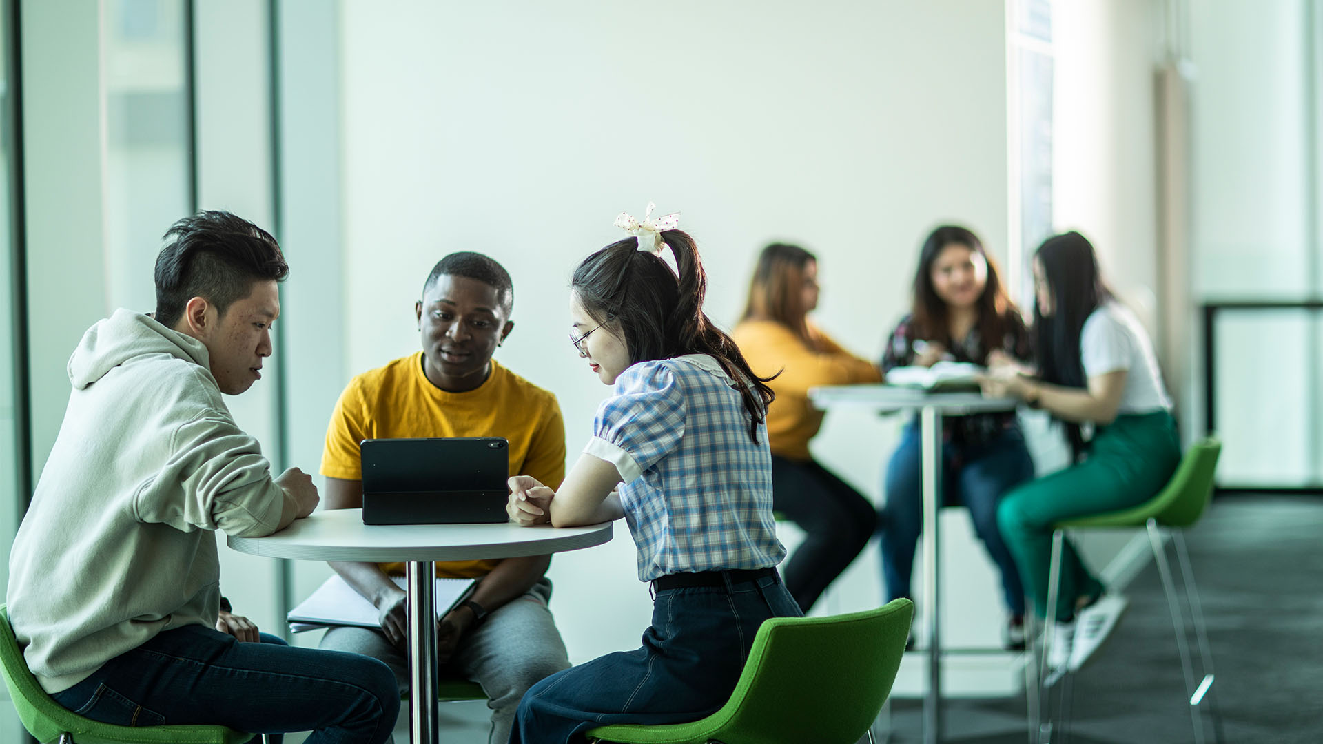Students sat on tables in a bright and airy breakout room