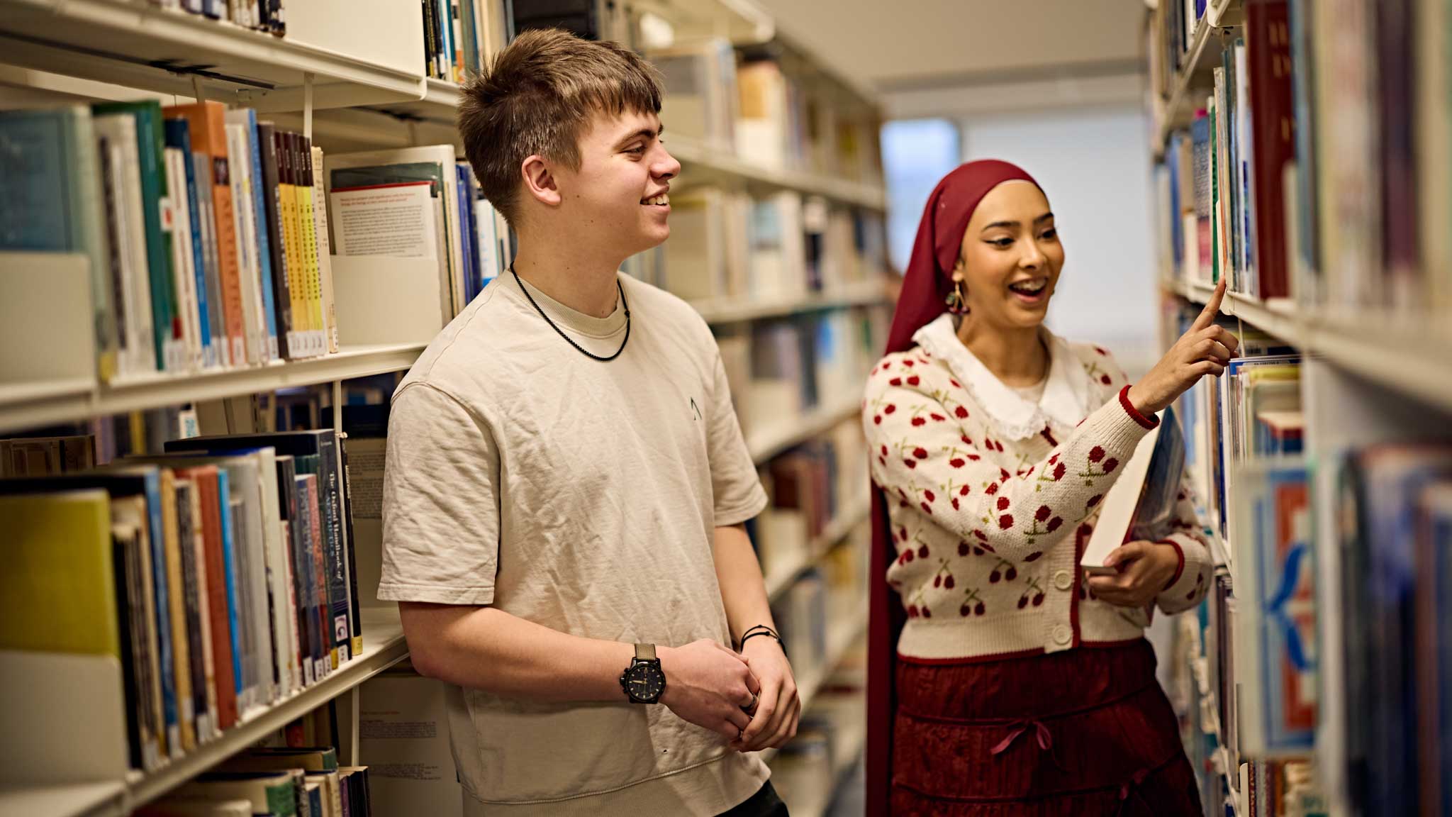 Two students searching for a book in the library