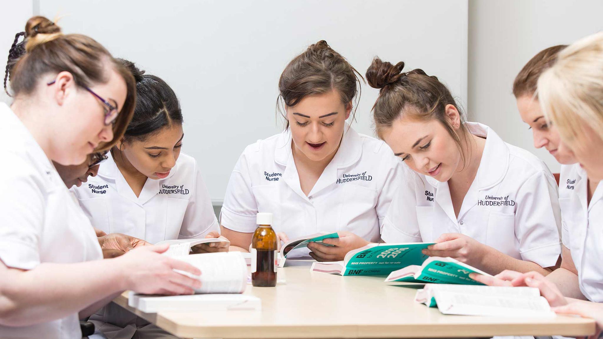 Students reading a book on how to safely administer medication