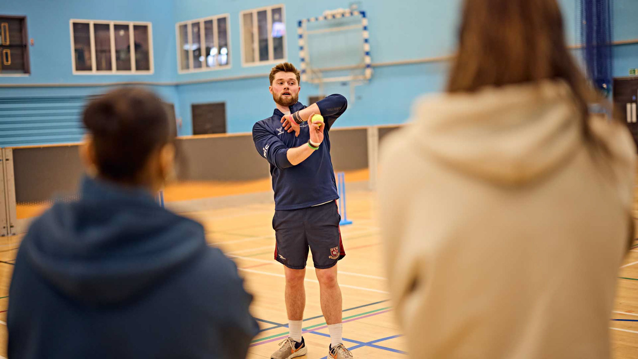 Sports coaching student demonstrating correct technique to athletes